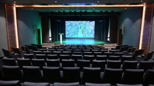 Close-up of a white d&b audiotechnik 24C cardioid column loudspeaker mounted on the auditorium wall.