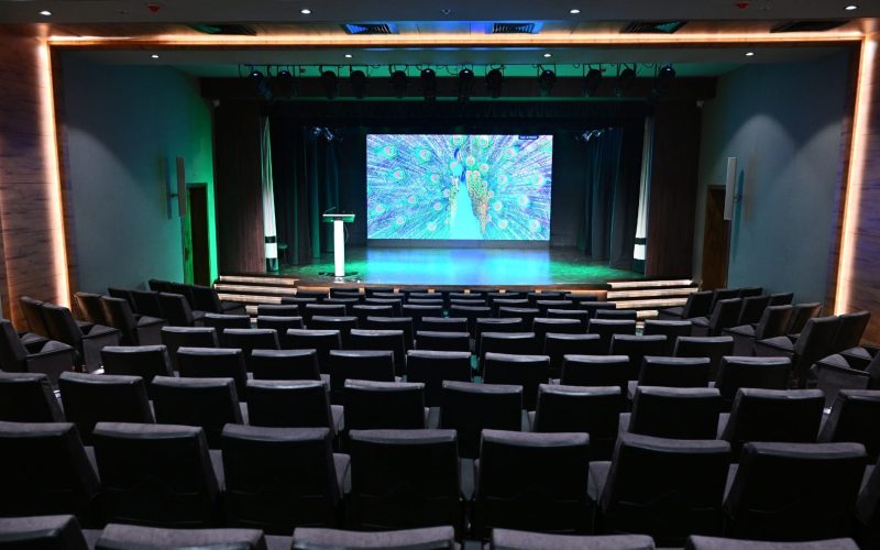 Close-up of a white d&b audiotechnik 24C cardioid column loudspeaker mounted on the auditorium wall.