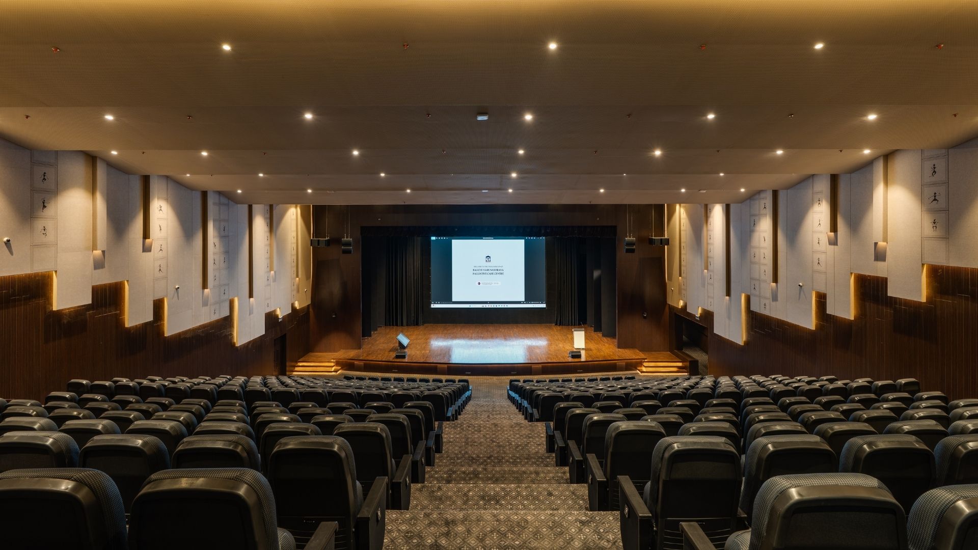 Interior of the 500-seater auditorium at Bagchi Karunashraya featuring Unilumin LED wall and acoustic wall treatments.
